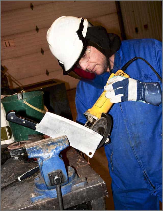 A worker sharpening a knife with a grinder