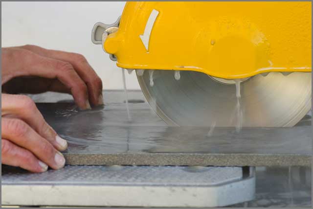 A worker cutting through porcelain with a diamond blade saw