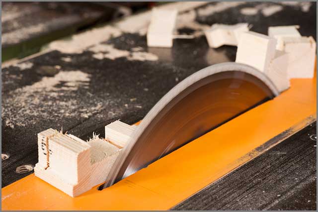 Image of a table saw blade in action in a woodworking workshop