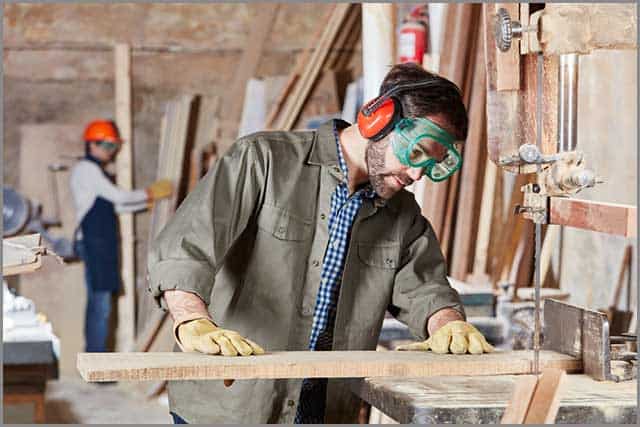 A man using the band saw for his woodcutting proc