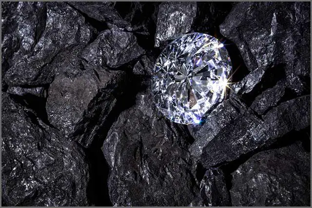 A single solitaire diamond among some pieces of coal