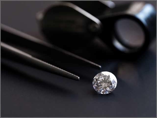 A diamond with tweezers and a magnifying glass