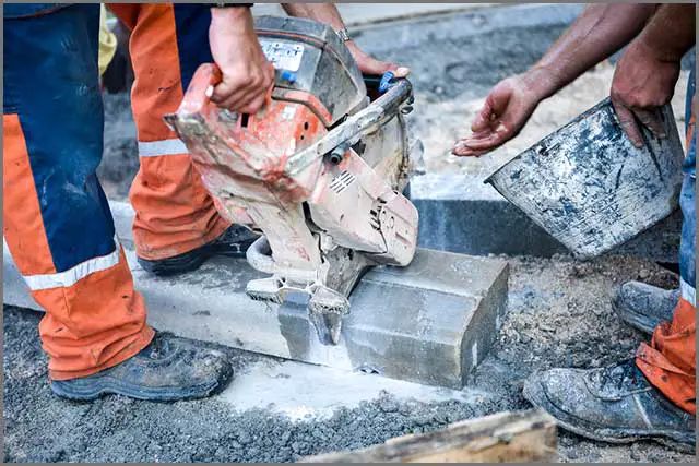 Contractors cutting concrete while wetting the blade.