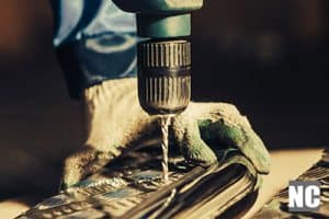 A workman drilling holes into a surface with a drill bit