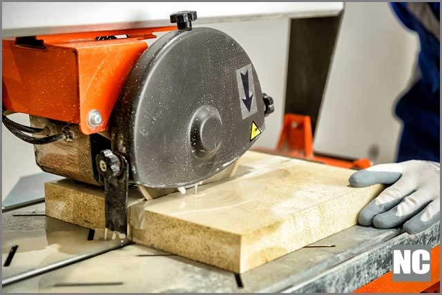 Worker cutting marble tiles using wet tile saw