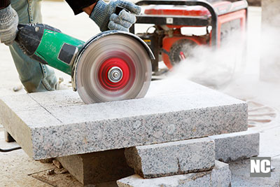 A machine operator cutting a granite slab