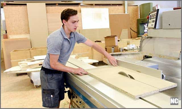 A woodworker making rip-cut using a table saw