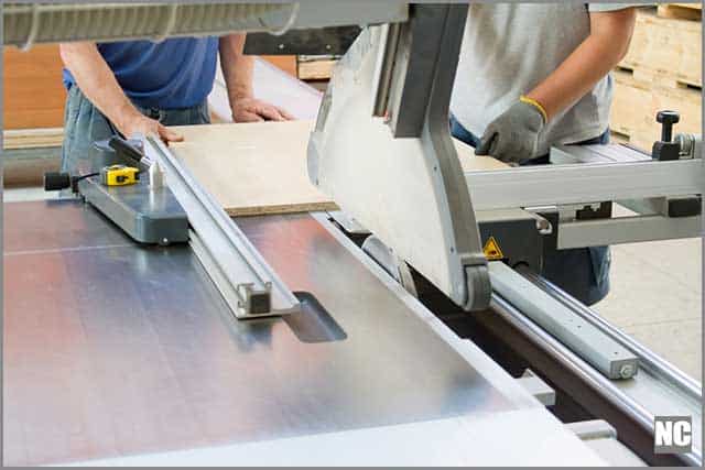 Men carefully handling the table saw during cutting.