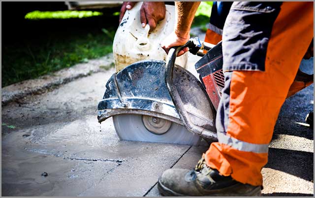 Man operating wet-cutting concrete using a hand-held saw.