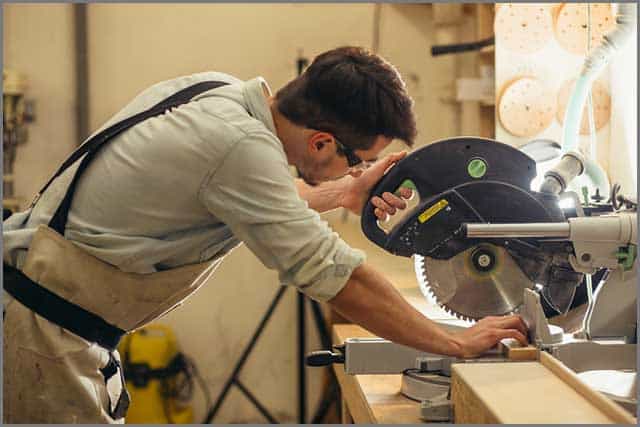 A worker cutting wood with a circular saw blade