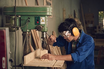 Operator seen using a drill press