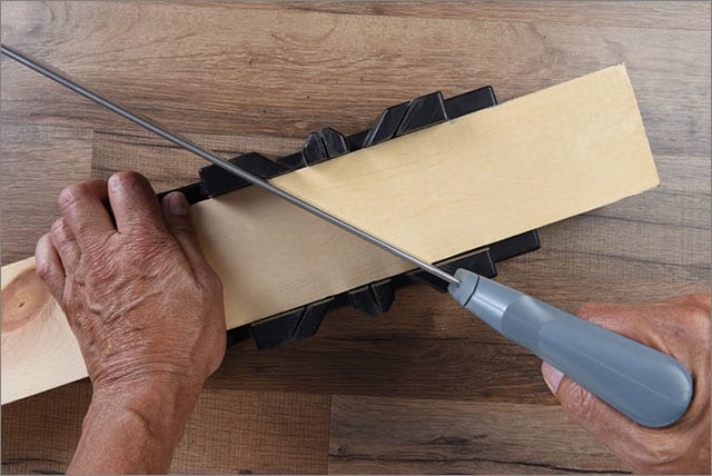 Using a handsaw and miter box to cut aboard