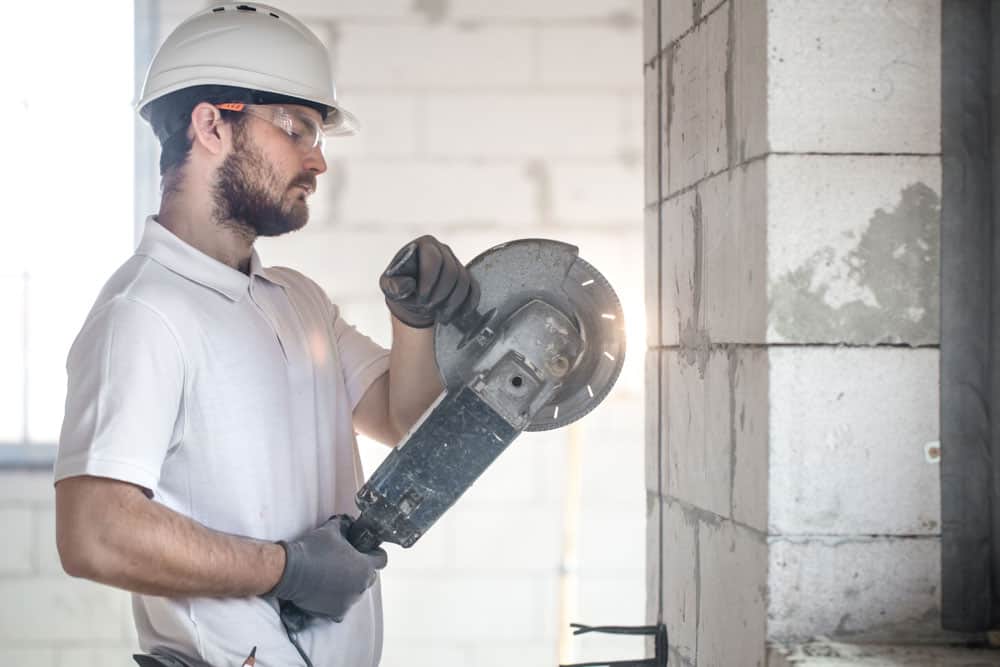 A worker operating an angle grinder with proper safety gear
