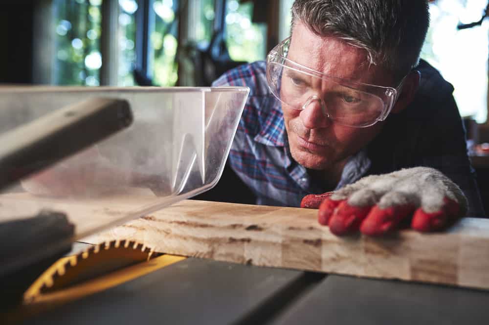 A man with safety equipment operating a table saw