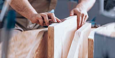 A woodworker uses sandpaper