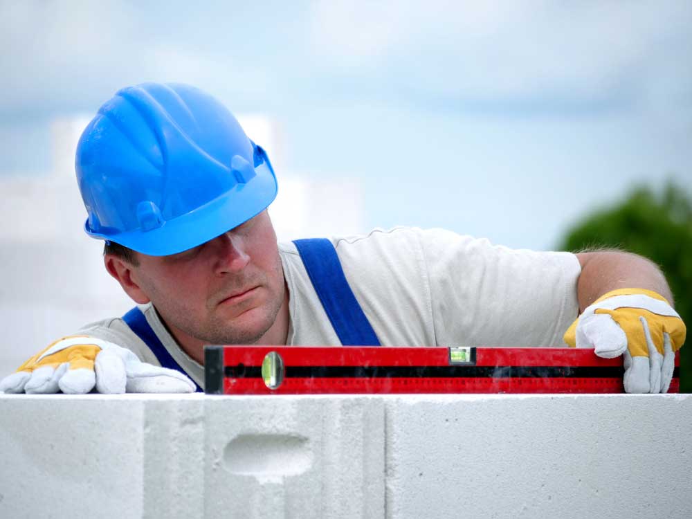 Worker checking the horizontal level of a house