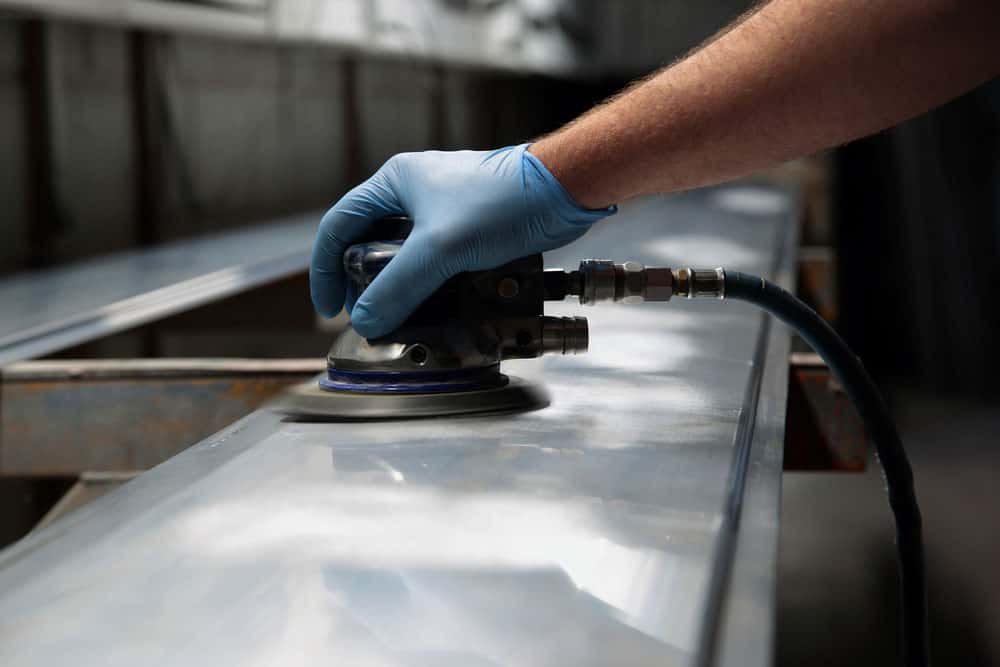 Man Polishing Steel with an Orbital Sander