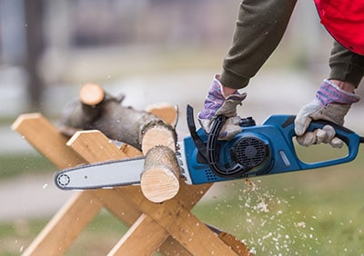 A man is cutting a branch with a chainsaw.