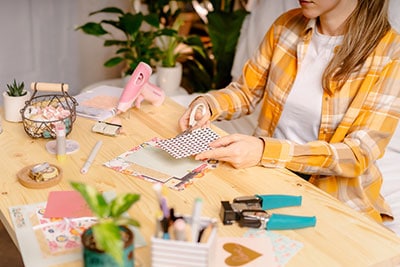 A woman is using paper to make a scrapbook