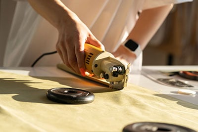 A clothes designer cutting fabric using a fabric cutter.
