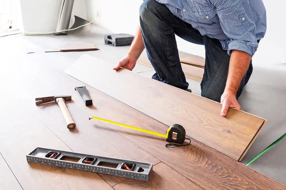 A man is installing laminate wooden flooring.