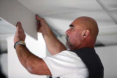 A tradesman is installing drywall.