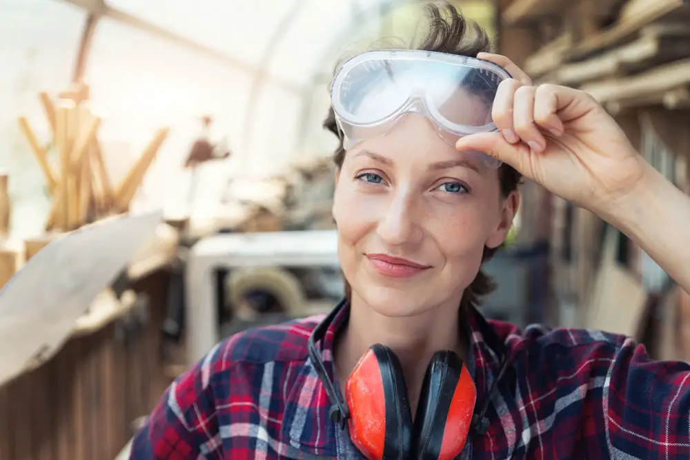 A female carpenter is wearing protective goggles.
