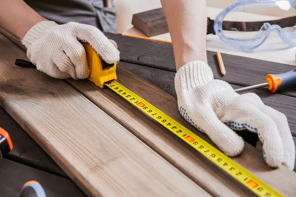 A carpenter is measuring the length of wood planks.