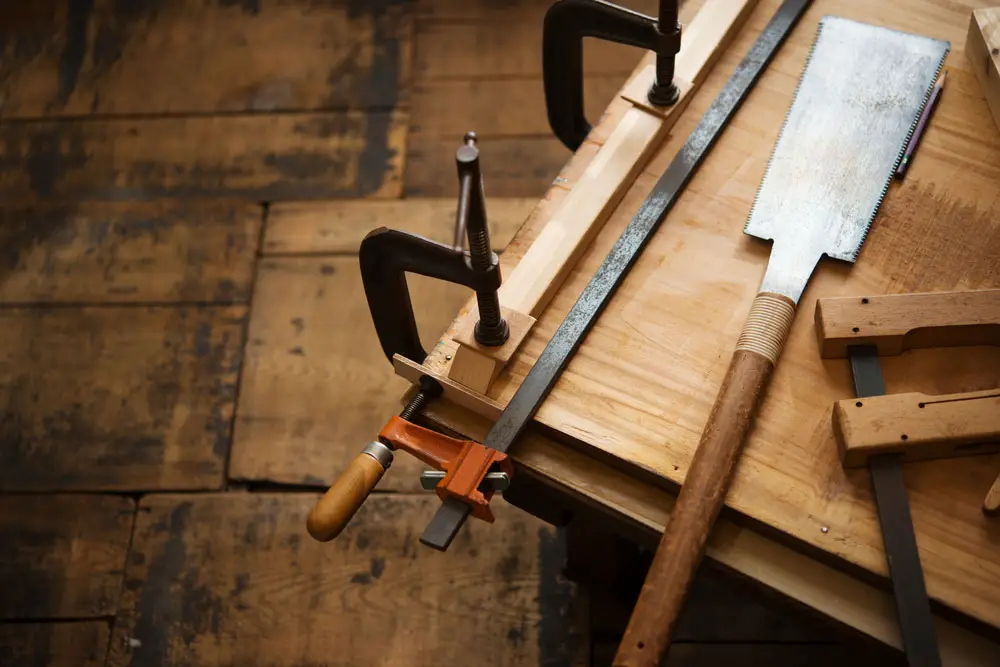 A bar clamp is clamping pieces of wood.