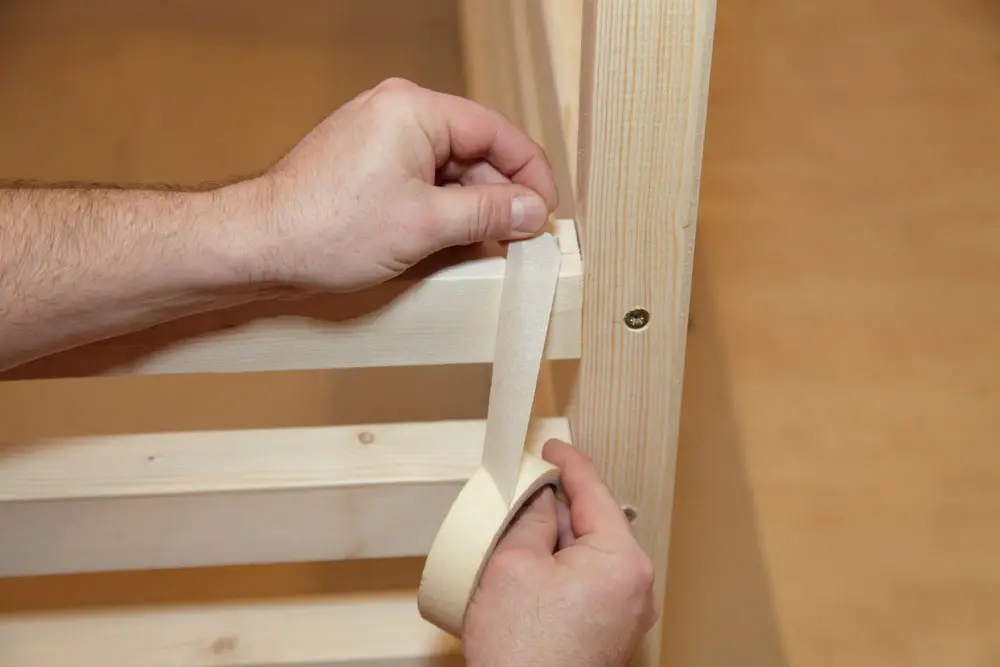 A carpenter is using masking tape.